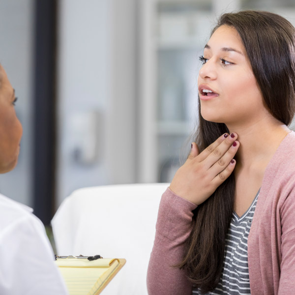 woman pointing to her throat